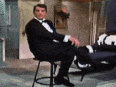 a man in a tuxedo is sitting on a bar stool