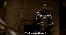 a man in armor is holding a goblet and says c'est magnifique