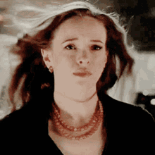 a woman wearing a necklace and earrings is making a face