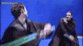 two men are fighting with lightsabers in front of a blue background with the hashtag @gillardstunts on the bottom