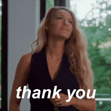 a woman in a black dress is standing in front of a window and says thank you