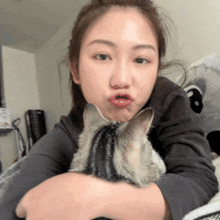 a woman is holding a cat in her arms and making a funny face