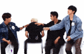 a group of young men are hugging each other while sitting on chairs .