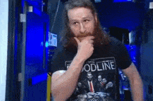 a man with long hair and a beard is wearing a black t-shirt that says `` the foodline '' .