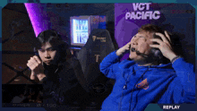 a man in a blue hoodie sits in front of a vct pacific sign