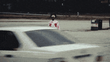a man in a bloody shirt is standing in front of a car