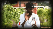 a man wearing a black hat and a white shirt has the website sakamoke.org on the bottom