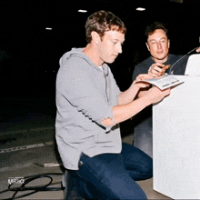 elon musk and mark zuckerberg are looking at a white box
