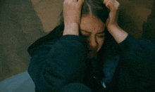 a woman is holding her head in pain while sitting down .