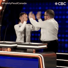 two men are giving each other a high five in front of microphones on a television show .
