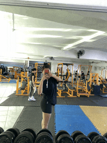 a woman taking a picture of herself in a gym with a sign that says ' a ' on it
