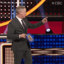 a man in a suit and tie holds a bag that says family feud