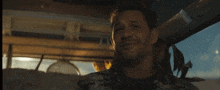 a man in a hawaiian shirt is smiling in a car
