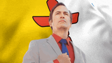 a man in a suit and tie stands in front of a yellow and white flag with a red cross on it