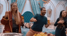 a group of people are dancing in a room with a bed and a bowl of grapes .
