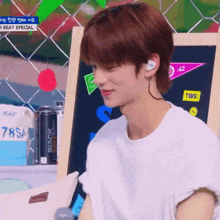 a young man wearing headphones and a white shirt is sitting in front of a blackboard .