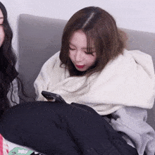 a woman wrapped in a white blanket is looking at her phone