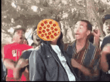 a man with a pizza in front of his face is surrounded by other people