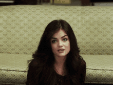 a woman is sitting on a couch and making a funny face