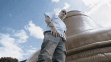 a man with a mask on his face stands in front of a giant object