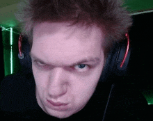 a close up of a man wearing headphones making a face