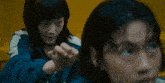 a woman in a blue jacket is standing next to a man in a yellow shirt