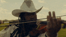 a man wearing a white cowboy hat is playing a violin