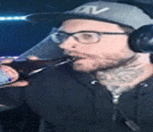 a man wearing a hat and headphones is drinking from a bottle