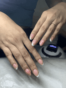 a woman 's nails are painted in pink and white with a gold border