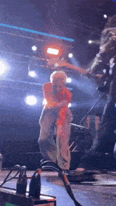 a man is playing a guitar on a stage while another man is standing behind him .