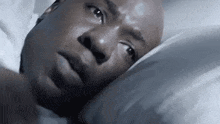 a man is laying in bed with his head on a pillow looking up .