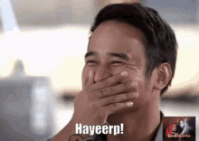 a man is laughing while covering his mouth with his hand and saying hayeerp !