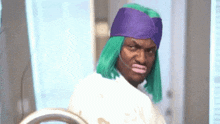 a man wearing a green wig and a purple hat is standing in front of a mirror .