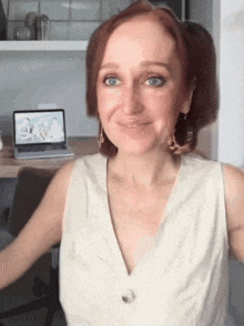 a woman with red hair is smiling in front of a laptop .