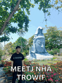 a man stands in front of a statue with the words meetjnha trowif written on the bottom