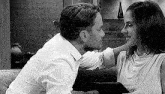 a man and a woman are sitting next to each other on a couch and kissing .
