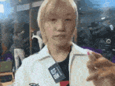 a young man with blonde hair is wearing a white jacket and a tag that says ' seoul ' on it