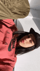 a woman wearing a red nike sweatshirt and a black hat