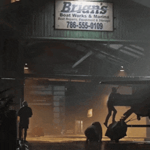 a sign for brian 's boat works & marina hangs above a garage door