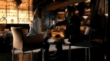a man and a woman are sitting at a table in a dark room drinking wine .