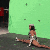 a woman is kneeling in front of a green screen with crosses on it