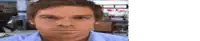 a man in a blue shirt is looking at the camera in a blurry room .
