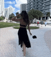 a woman in a black dress is walking down a brick sidewalk .