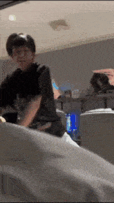 a man in a black shirt is sitting on a bed in a room