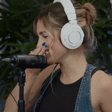 a woman wearing white headphones is singing into a microphone that says rode