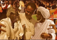 a man in a white turban talks to two other men in front of a crowd
