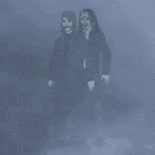 two ghosts are standing next to each other in a foggy room .