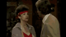 a man and a woman are kissing in a room . the woman is wearing a bandana .
