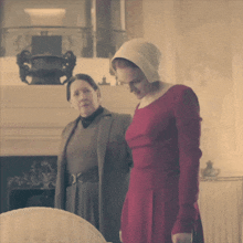 a woman in a red dress stands next to an older woman in a grey dress