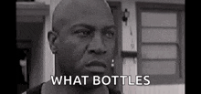 a black and white photo of a bald man standing in front of a house with the words `` what bottles '' .